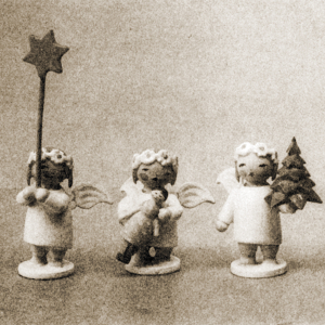 [Translate to Englisch (Intl):] Drei Margeritenengel. Sie halten jeweils einen Stern, ein Bäumchen und eine Puppe. Schwarz-Weiß-Aufnahme.