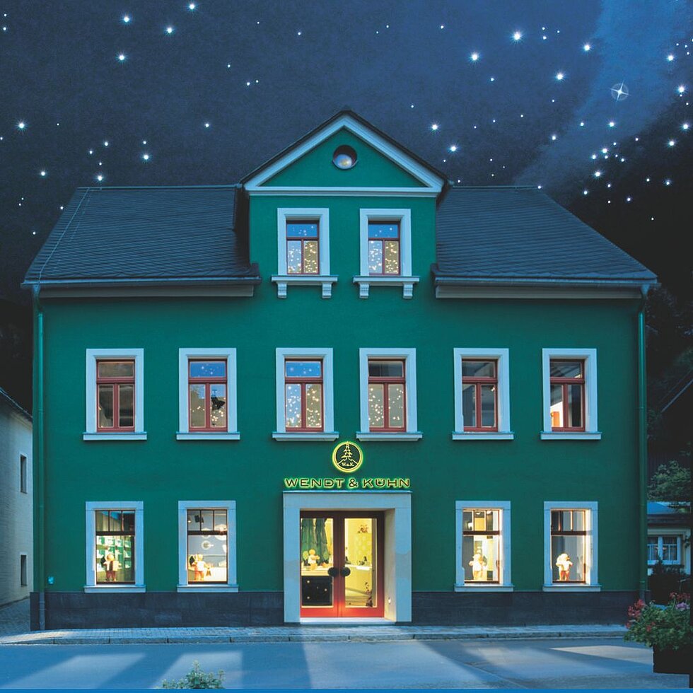 [Translate to Englisch (int):] Grünes Haus der Figurenwelt in Seiffen unter nächtlichem Sternenhimmel