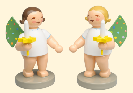 Two angel figurines with color-dotted green wings, white dresses and candles in yellow holders, standing on grey pedestals