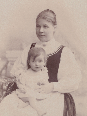 [Translate to Englisch (Intl):] Historische Schwarz-Weiß-Fotografie. Olly als Baby auf dem Schoß ihrer Mutter.