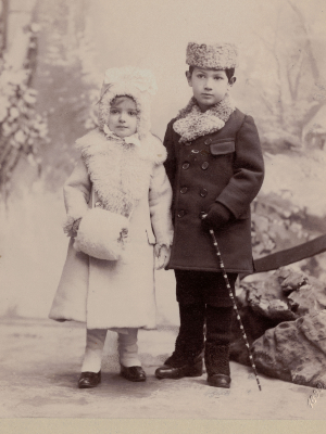 [Translate to Englisch (Intl):] Historische Schwarz-Weiß-Fotografie. Olly und Herbert als Kinder. Olly trägt einen hellen Wintermantel, Herbert einen dunklen.